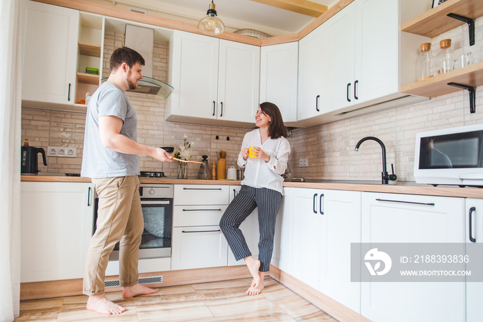 couple talking at the kitchen. man cooking breakfast