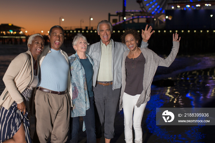 Portrait happy senior friends dancing on beach at night