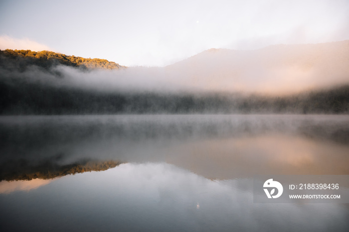 Foggy lake scape and vibrant autumn colors in trees at amazing misty sunrise .Sfanta Ana,Romania,Tra