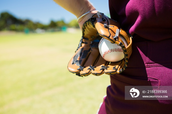 Mid section of baseball pitcher holding ball in glove