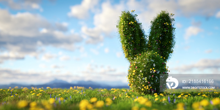 Easter bunny made of spring grass and flowers on green meadow.