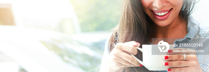 Blurred image of a Caucasian woman holding a cup of coffee enjoying coffee smiling happily standing by the window in a cafe and restaurant