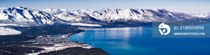 Aerial view of Lake Tahoe on a sunny winter day, Sierra mountains covered in snow visible in the background, California