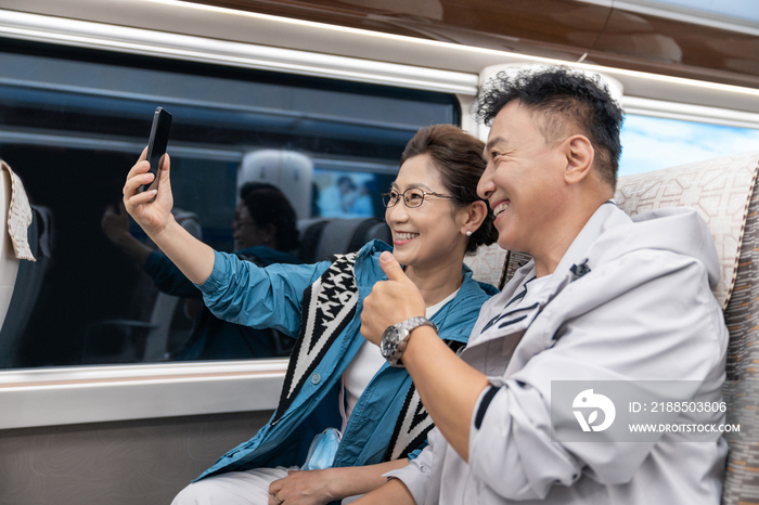快乐的老年夫妇坐地铁用手机自拍