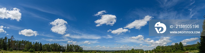 panorama white fluffy clouds on blue sky over foresty landscape