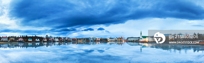 Beautiful panorama of the skyline cityscape of Reykjavik, reflected in lake Tjornin at the blue hour in winter