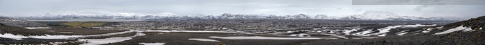 Iceland highlands autumn ultrawide view. Lava fields of volcanic sand in foreground. Hrauneyjalon lake and volkanic snow covered mountains in far.