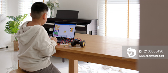 Young asia student remotely learn online at home in coding robot car and electronic board cable in STEM, STEAM, mathematics engineering science technology computer code in robotics for kids concept.