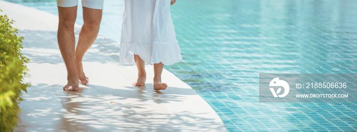 Young couple walking together by the pool.