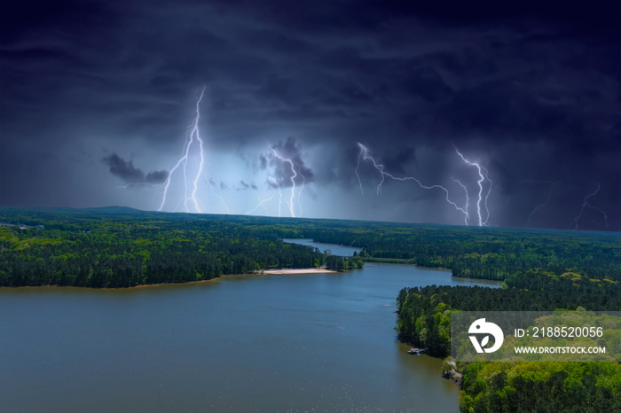 an aerial shot of the silky green waters of Lake Acworth surrounded by miles of lush green trees with boat houses and docks along the banks and storm clouds   and lightning  at Dallas Landing Park