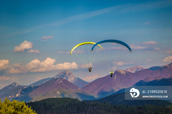 Flying paragliders from the Stranik hill over the mountainous landscape of the Zilina basin in the north of Slovakia..Mala Fatra National Park in the background, Slovakia, Europe.