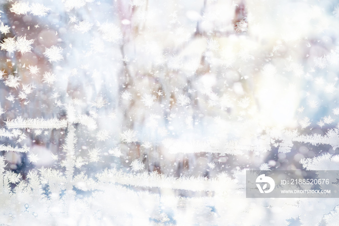 Winter landscape through a frozen window. Blurred snow background. Trees and plants covered with snow.