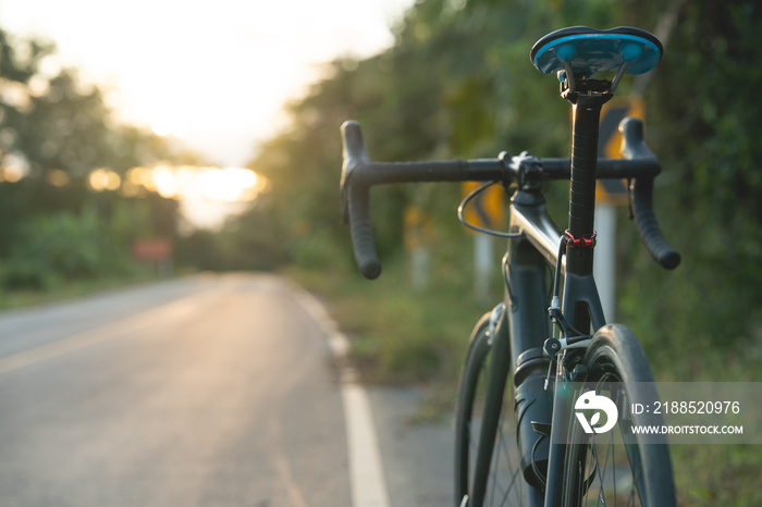 Road bike parked on a beautiful road sunset, warm light with copy space.