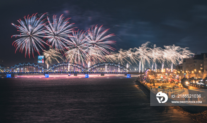 Colorful fireworks in Riga city with panoramic view over the river Daugava and railroad bridge. New year celebration.