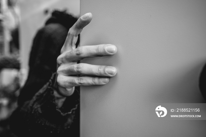 Closeup of a beautiful and stylized hand of worker with blue hoodie holding a metal door in the day (in black and white)