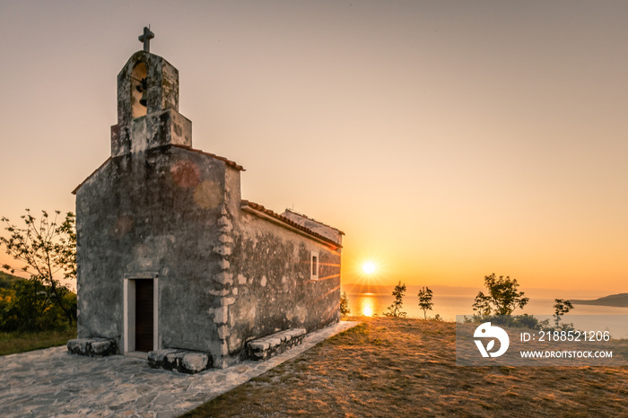 Beautiful little church by the sea in sunrise or sunset. Landscape shot in backlight with a view of the sun. beautiful colorful clouds