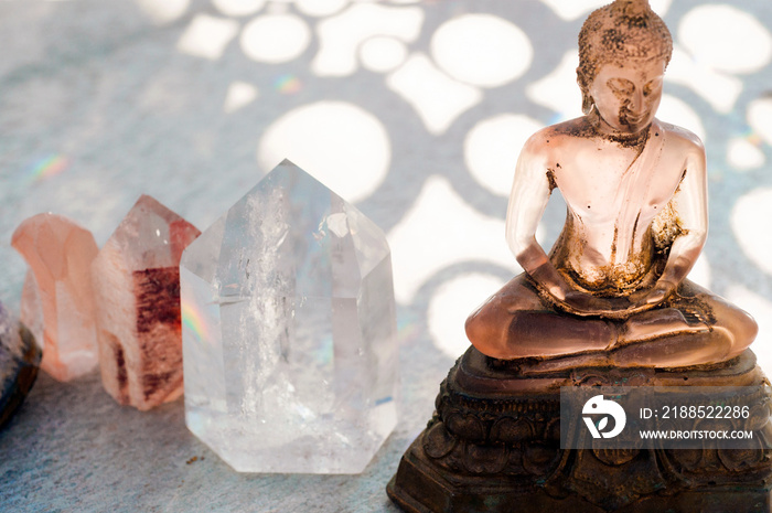 Translucent pink Buddha statue with healing Reiki crystals and subtle rainbow light.