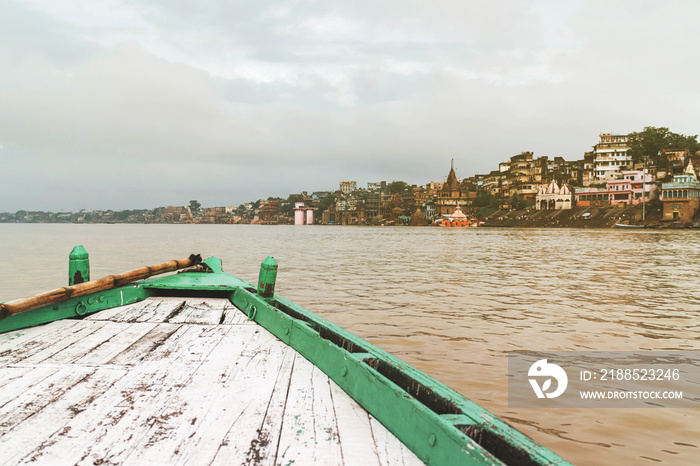 Front of the green boat floating on the Ganga River is heading to pray at The holy Dasaswamedh Ghat, near Kashi Vishwanath Temple, Varanasi, India.