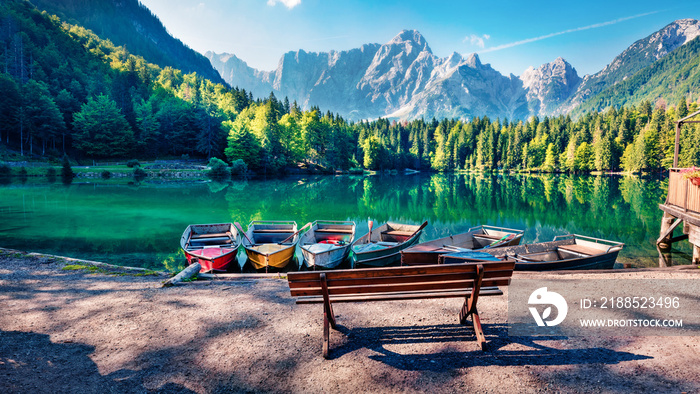 Six pleasure boats on Fusine lake. Spectacular morning scene of Julian Alps with Mangart peak on background, Province of Udine, Italy, Europe. Traveling concept background.