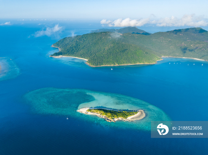 Stunning aerial high angle view of Black Island with a beautiful reef and Hook Island in the background, both part of the Whitsunday Islands group near the Great Barrier Reef in Queensland, Australia.