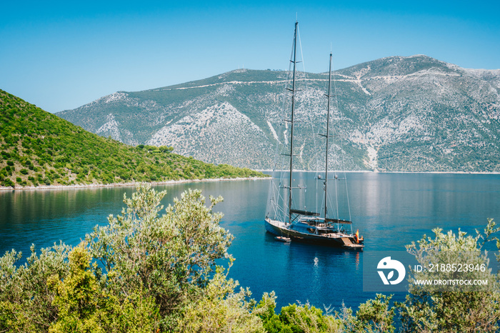 Summer vacation in Greece. Luxury black private yacht at anchor in beautiful sea lagoon. Ithaka island