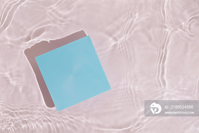 Summer scene with blue paper card note in water. Sun and shadows. Minimal nature background with creative copy space.