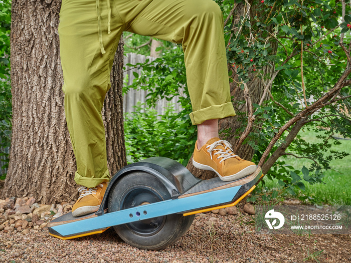 riding one-wheeled electric skateboard in a backyard or park