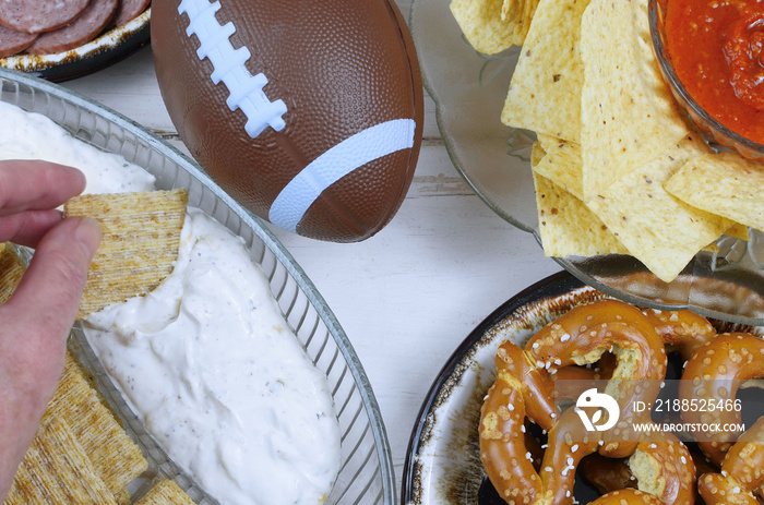 Snacks for watching a football game. Great for Super Bowl or Playoff themed projects. Pretzels, sausage, chips and dips with a football and a faux grass background