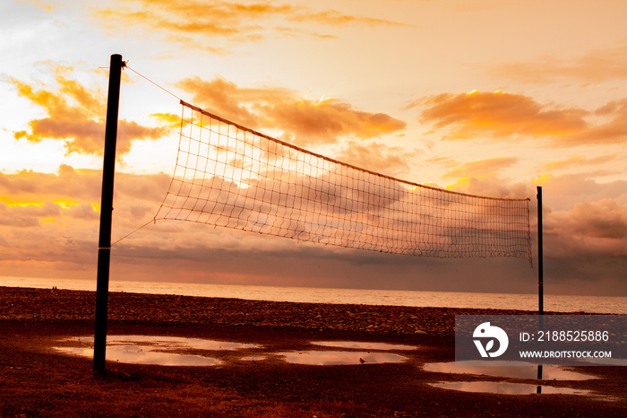 Beach volleyball net after the rain against the background of the sea at sunset. Beach and sports games