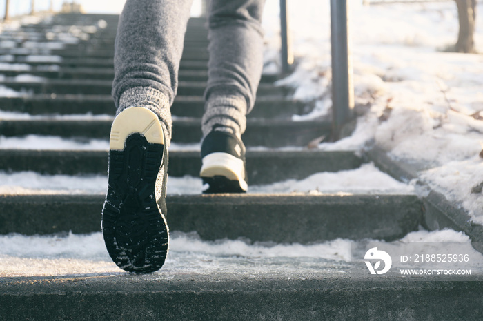 Legs of sportive woman running up stairs in winter, close up view