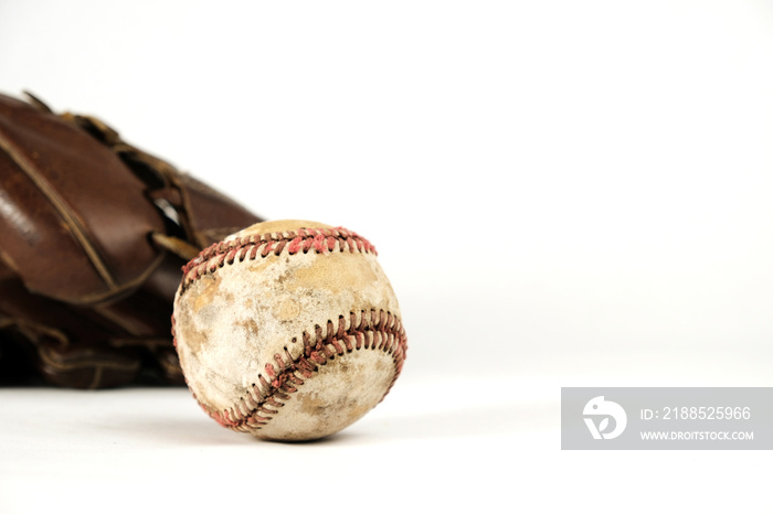 Old baseball with leather glove in background, isolated sports equipment.