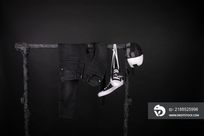 Sale sign. Black and white sneakers, cap  pant, jeans hanging on clothes rack   background.   friday. Copy space.