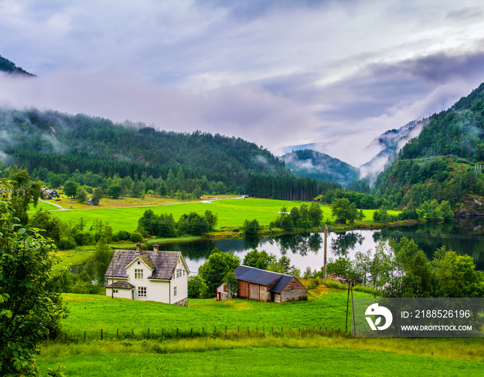 Typical countryside Norwegian landscape with houses on the shore of the lake. Cloudy summer morning in Norway, Europe. Artistic picture. Beauty world.