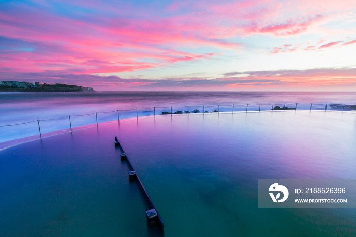Pink colorful sunrise over Bronte rock pool.