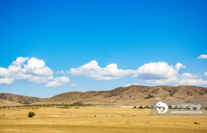 Desert landscape. Blue sky with white clouds. Summer steppe landscape. Hot desert with mountains view.