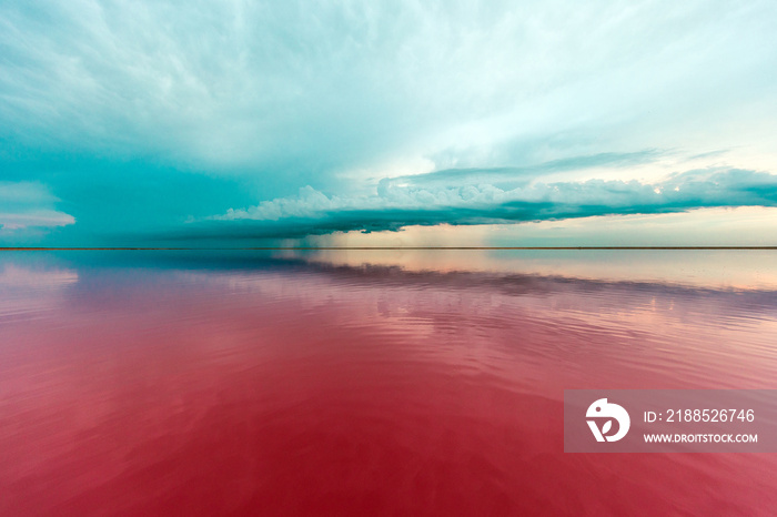 pink lake and sandy beach with a sea bay under a blue sky with clouds