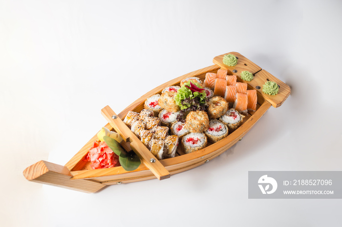 Wooden boat with lots of sushi with ginger and wasabi
