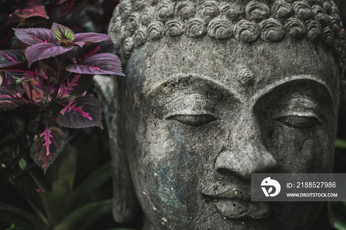 Stone Buddha face close-up. Handmade carved Buddha statue in balinese garden as decoration.