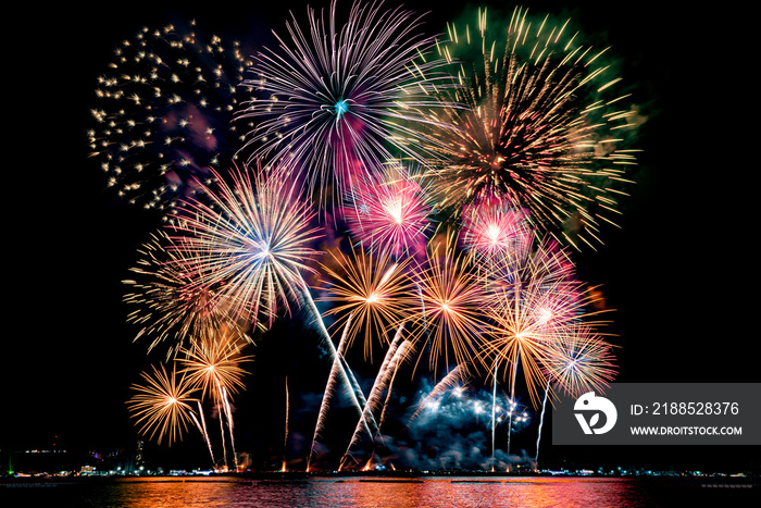 Amazing beautiful colorful fireworks display on celebration night, showing on the sea beach with multi color of reflection on water