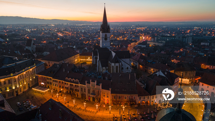 Birds eye view over historic city center of Sibiu, Romania at sunset. Aerial photography was shot from a drone at sunset with the Council Tower and a beautiful cityscape in view.