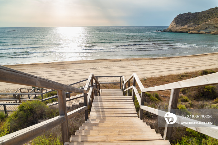 Wooden gangway with staircase leading to one of the beautiful beaches of  Cuatro Calas  area (meaning:  Four Coves ), Aguilas, Murcia, Spain. Sun and sky on the background.