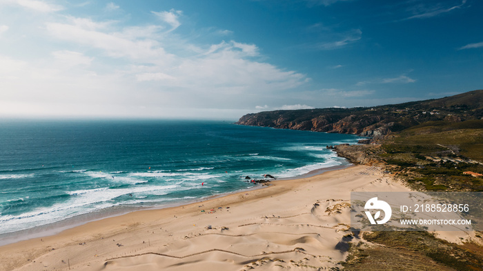 Drone aerial view of unidentifiable kitesurfers at Guincho beach in Cascais, Portugal