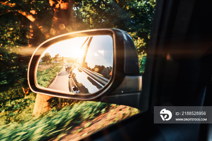 Car sunset road mirror. Summer sun, highway car road reflection in mirror. Vacation trip concept.