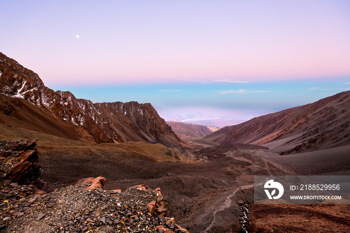 Mountain peaks at sunset with moon in Vallecitos, Mendoza. El Salto high altitude camp.