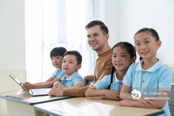 老师在课堂上辅导小学生用电脑