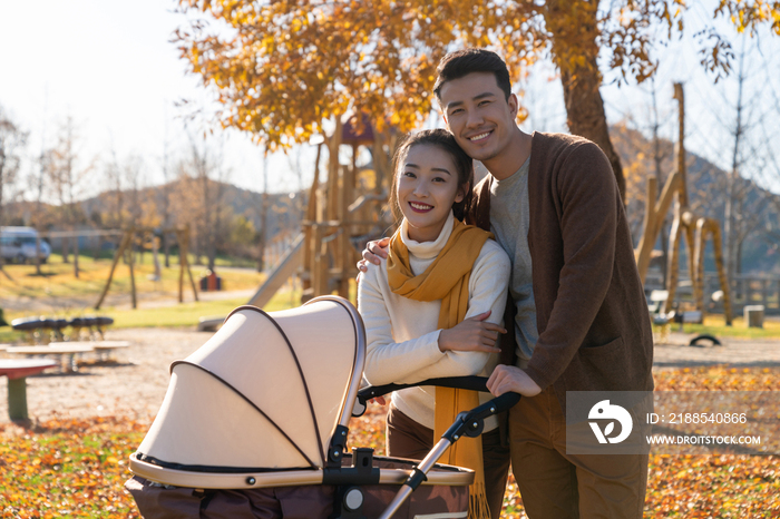 年轻夫妻推着婴儿车散步