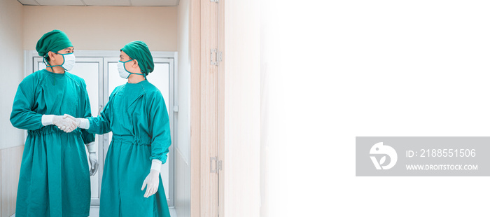 Two doctor wear protective scrub suit with glove,medical mask handshake after success result of surgery in hospital corridor,hallway. Professional team surgeons. Healthcare,Hospital emergency concept