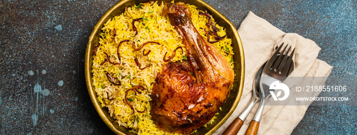 Delicious Indian dish Biryani chicken leg with basmati rice in metal brass old bowl on table rustic stone background. Traditional non-vegetarian food of India