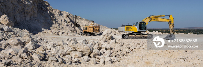 A large yellow tracked excavator is mining rock in a quarry.