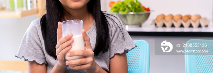 Portrait of a satisfied children holding glasses of milk in kitchen in morning. Cute little girl with glass of milk, copy space for text or product advertising your. kids, healthy, lifestyle concept